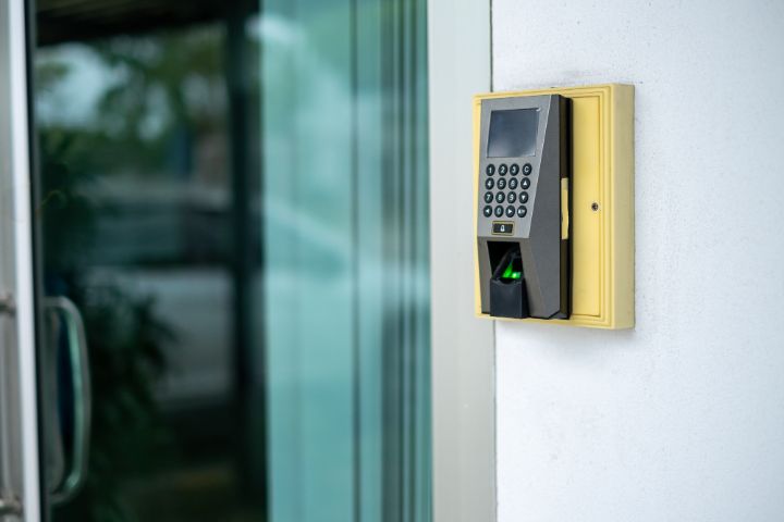 Fingerprint and keypad access control reader mounted beside a glass door