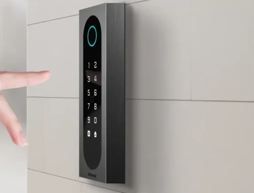 Akuvox touch keypad access reader mounted on a tiled wall as a hand reaches toward it